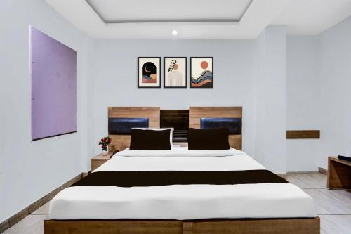 a bedroom with a large bed and paintings on the wall at Super Hotel O Haldwani Near Bus Stand in Haldwāni