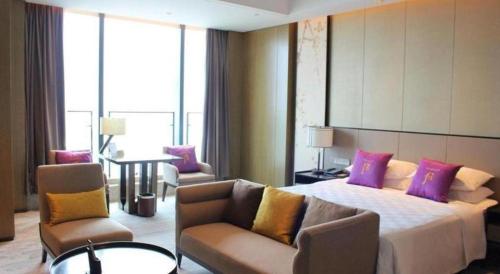 a hotel room with a bed and a couch and chairs at Golden Eagle Summit Hotel Kunshan in Suzhou