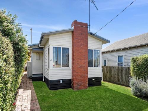 a house with a brick chimney in a yard at Cute cottage in a Supreme Location in Geelong