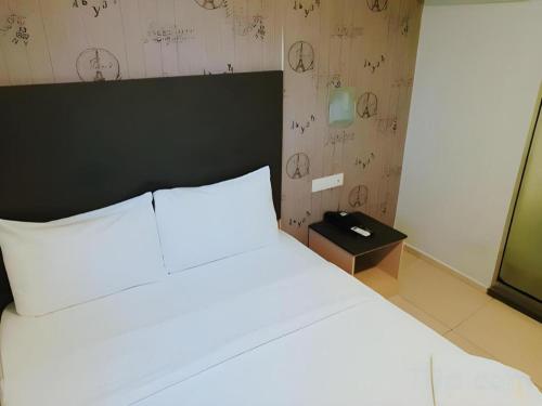 a bedroom with a white bed with a black headboard at City View Hotel At KLIA & KLIA2 in Kuala Lumpur