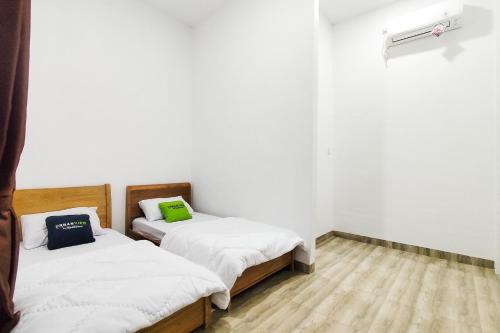 two beds in a room with white walls and wooden floors at Urbanview Hotel Syariah at Glory Guest House Kota Baru in Sultan Thaha Airport