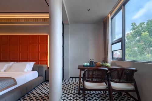 a bedroom with a bed and a table and a window at 诺亚度假酒店 in Luang Prabang