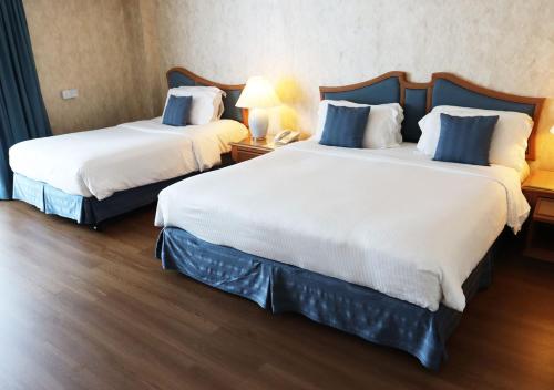 a hotel room with two beds and a lamp at Grand Palace Hotel in Miri