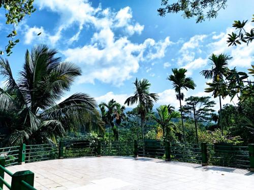 a fence with palm trees and a blue sky at Ayurweda spa Hotel in Deniyaya