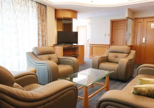 a living room with couches chairs and a television at Grand Palace Hotel in Miri