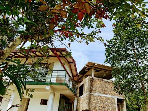 a building with a balcony and a tree at Ayurweda spa Hotel in Deniyaya