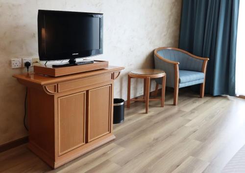 a tv on a wooden stand with a chair and a television at Grand Palace Hotel in Miri