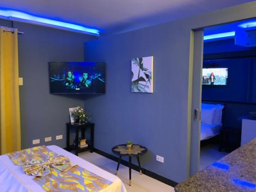 a blue room with a bed and a tv on the wall at TLT Condotl E-208 -Near Airport at Kiener Hills Condominium in Mactan