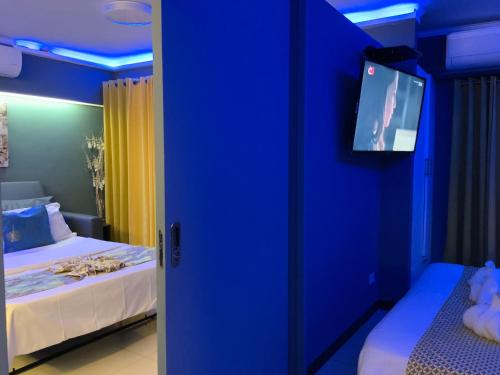 a blue room with two beds and a flat screen tv at TLT Condotl E-208 -Near Airport at Kiener Hills Condominium in Mactan