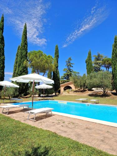 a swimming pool with two umbrellas and chairs and a pool at Borgo Melograno in Chiusi