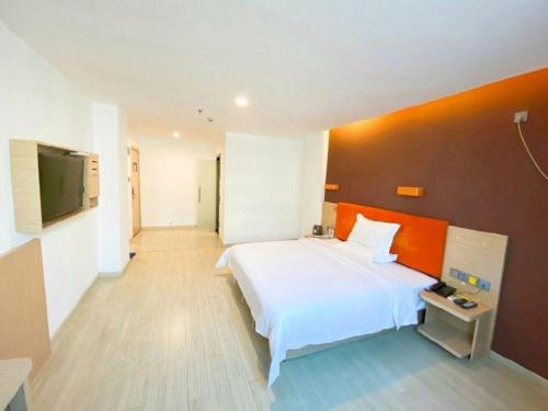 a bedroom with a white bed and an orange wall at 7 Days Premium Hotel Ji'an Taihe Gongnongbing Avenue in Ji'an