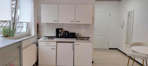 eine Küche mit weißen Schränken und einer Spüle in der Unterkunft Ferienwohnung in Großostheim