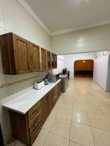 a large kitchen with wooden cabinets and a tile floor at Lar do Índico in Fombeni
