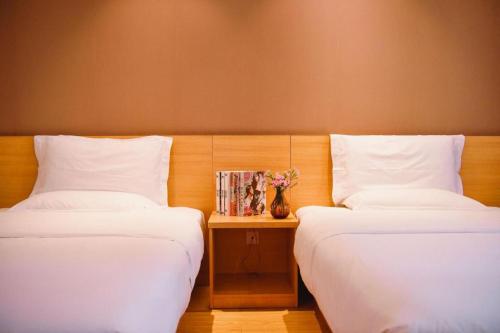 two beds sitting next to each other in a room at 7 Days Premium Chongqing Longtou Temple North Railway Station Center in Chongqing