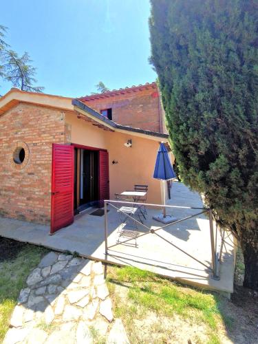 a house with a red door and a table and an umbrella at Borgo Melograno in Chiusi