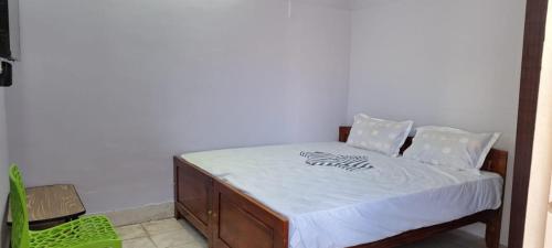 a bedroom with a bed with white sheets and a green chair at Nature Homestay in Tiruchchendūr