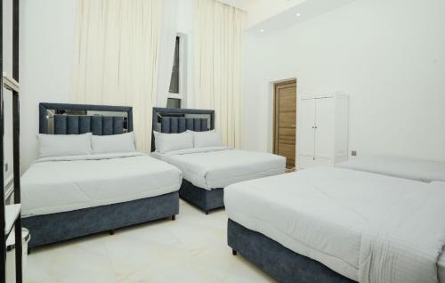 two beds in a room with white walls at Calm Zone Luxury Private Pool 5BHK Villa in Al Ḩalāh