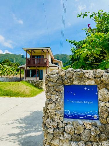 a stone wall with a sign in front of a house at 新築!一棟貸切ヴィラ Sea Garden Ishigaki 提携レンタカー割引有り! in Ishigaki Island