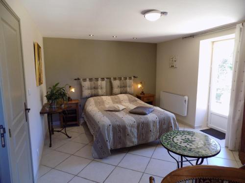 a bedroom with a bed and a table and a window at Le Jaonnet in Nabirat
