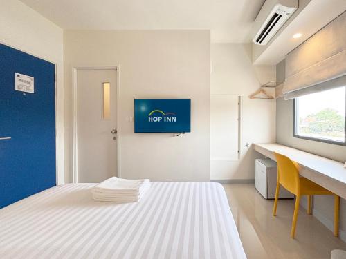 a bedroom with a bed and a desk and a tv on the wall at HOP INN Phrae in Phrae