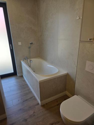 a bathroom with a bath tub and a toilet at Eko Osada Zacisze in Ostrowite