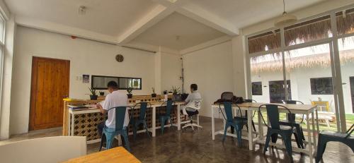 two men are sitting at tables in a restaurant at Camotes Hostel Resort in Camotes Islands