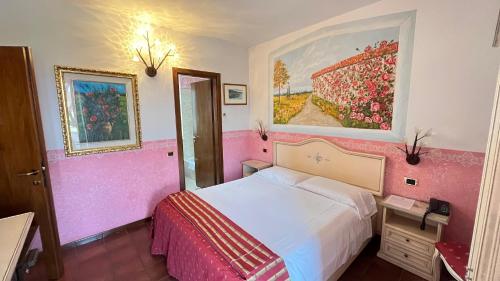 a pink bedroom with a bed and a painting on the wall at Hotel Bolero in Sirmione