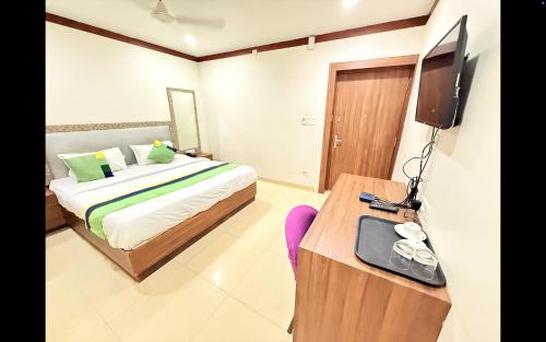 a bedroom with a bed and a tv and a table at Hotel Paradise Premium Rasulgarh in Bhubaneshwar