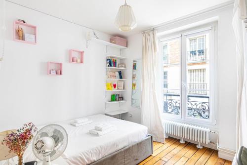 une chambre blanche avec un lit et une fenêtre dans l'établissement GuestReady - Family Retreat in Bastille, à Paris