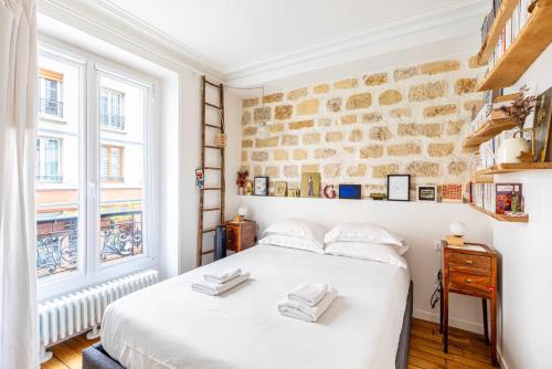 une chambre avec deux lits et un mur de briques dans l'établissement GuestReady - Family Retreat in Bastille, à Paris