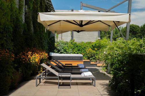 a group of chairs under an umbrella on a patio at VERSOVERDE HOTEL Alzaia Naviglio Grande in Milan