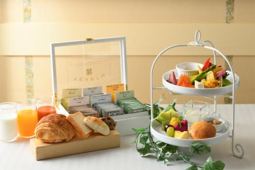 a table with a tray of food and a plate of fruit at Hotel Monterey Lasoeur Ginza in Tokyo