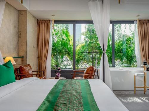 a bedroom with a large bed and a large window at CHECK inn Phnom Penh Royal Palace in Phnom Penh