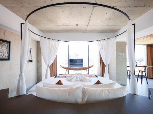 a bedroom with a large white bed with curtains at CHECK inn Phnom Penh Royal Palace in Phnom Penh