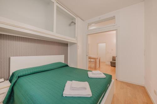 a bedroom with a green bed with two towels on it at Casa Falco - 15 min dalla stazione e dal centro in Padova
