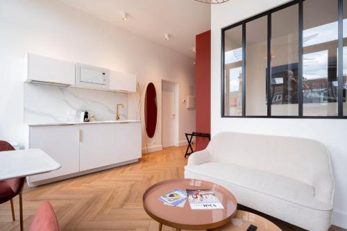 un soggiorno con un divano bianco e un tavolo di Les perchoirs de Stanislas 1 - logement de standing hyper centre a Nancy