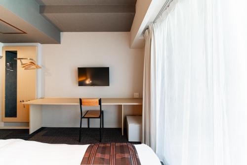 a hotel room with a bed and a desk with a chair at FL Hotel Asakusa in Tokyo