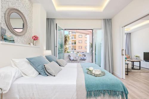 a white bedroom with a large bed with a mirror at Solaga - Centro Alameda in Málaga