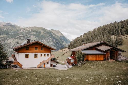 two buildings in a field with mountains in the background at Chalet Mittner Wirt Grosskirchheim in Mitten