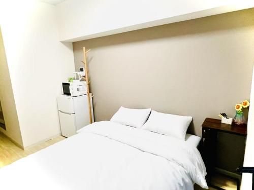 東京にあるサクラシャドウ東池袋の部屋にある白いシーツと枕が置かれたベッド