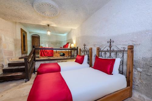 a bedroom with a bed with red pillows at Onur Cave Cappadocia in Goreme