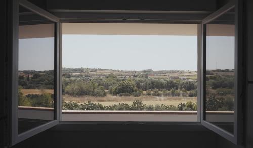 an empty room with a large window with a view at Mhometredici Guest House in Sestu