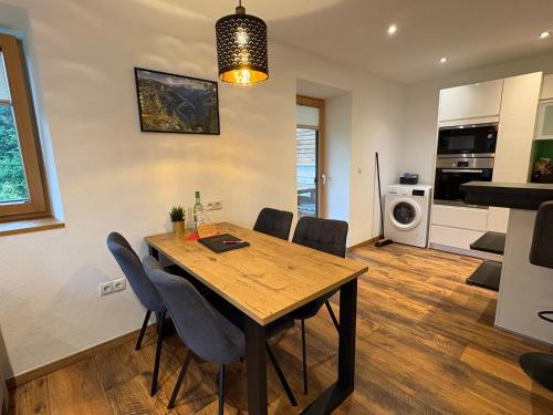 a kitchen and dining room with a wooden table and chairs at Modernes Serviced Apartment - FeWo Land Idyll in Dürrnberg