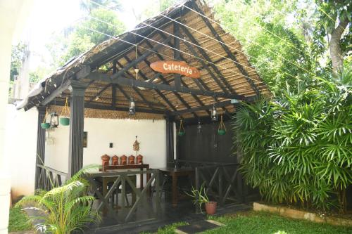 a pergola with a table in a garden at Traget safari home stay in Udawalawe