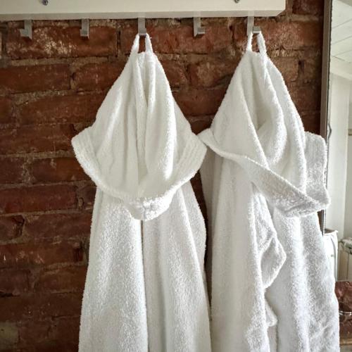 three white towels hanging on a wall in front of a mirror at Appartamento Cà Insulae in Luni