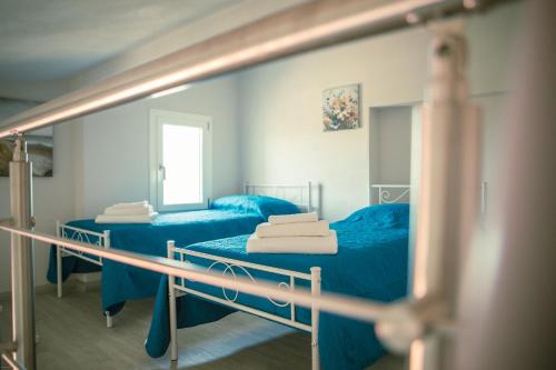 a room with two beds with blue sheets and a mirror at Mhometredici Guest House in Sestu