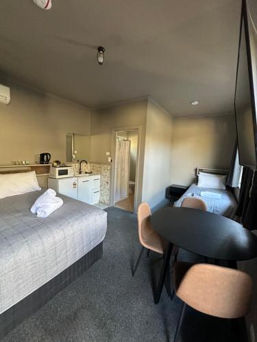 a bedroom with a bed and a table and a kitchen at Calder Family Motel in Bendigo