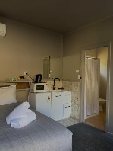 a bedroom with a bed with a microwave and a kitchen at Calder Family Motel in Bendigo