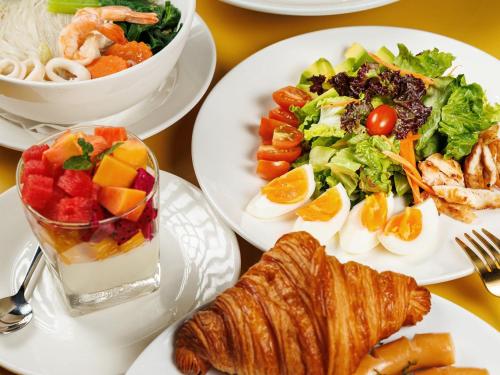 a table with plates of food and a salad at CHECK inn Phnom Penh Royal Palace in Phnom Penh