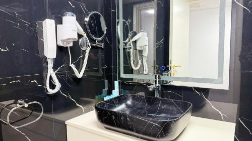a black bathroom with a black sink and phones at Royal Tulip Dancenter Suites Sharjah in Sharjah